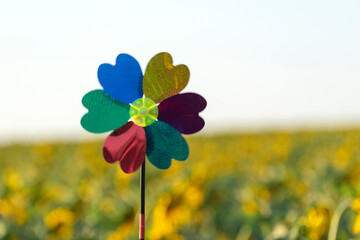 Windmill toy on yellow field background. Alternative energy concept.