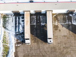 Aerial Follow Shot of White Semi Truck with Cargo Trailer Attached Moving Through Industrial Warehouse, Rural Area.