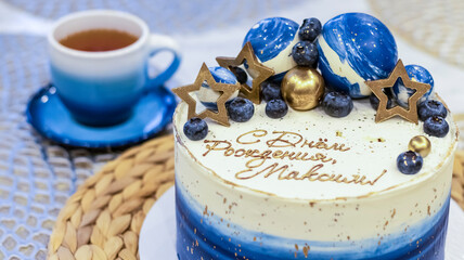 Handmade birthday cake on a blurred background with balloons and sparkles. Cheesecake cake, blue and gold accents. Festive background for postcard, holiday, birthday, anniversary, 18 years. 