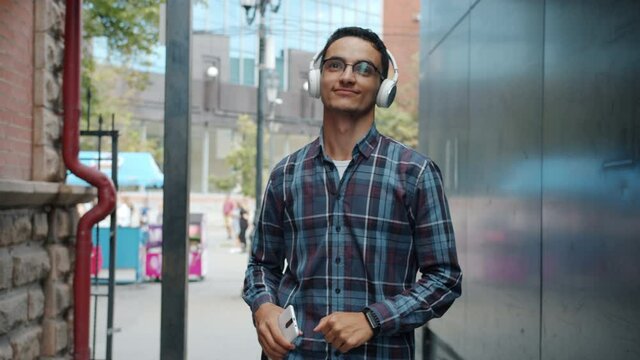 Slow motion of happy Arab guy listening to music outside using smartphone and headphones dancing having fun enjoying leisure time alone. People and devices concept.