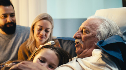 Aged male patient hugging grandchildren near parents