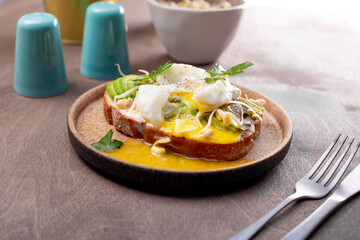 Light summer breakfast - sandwich with avocado, cottage cheese, sprouted beans and poached egg on the table close up