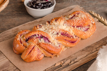 Fresh baked goods - delicious wicker bun on wooden background