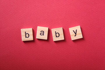 The word "baby" made from wooden cubes on a red background