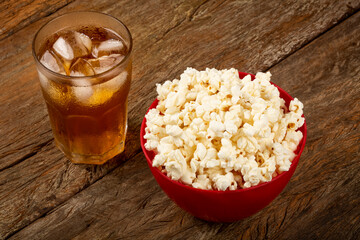 Bowl with salted popcorn and soda on the table.