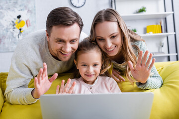 Cheerful family having video chat on laptop in living room.
