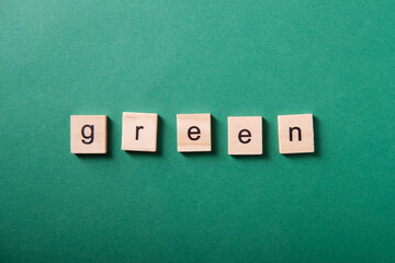 Word "green" made from wooden cubes on a green background