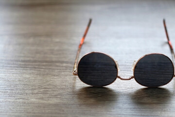 Fototapeta na wymiar Round retro sunglasses on wooden table. Selective focus.