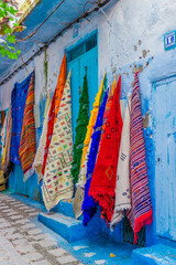 Selling colorful handmade carpets and bedspreads for tourists on the streets in medina of Chefchaouen or Chaouen town, Morocco.