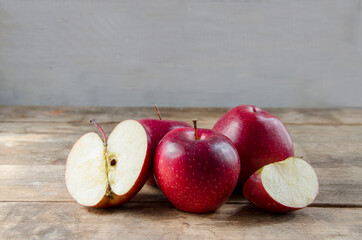 A composition of red apples, cut and whole, on a light, vintage background. Half and a quarter of the fruit. Natural fruits.
