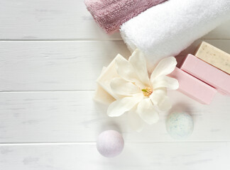 SPA soap banner. Aromatic natural soap with magnolia flowers, and bath bomb on a wooden white background, top view
