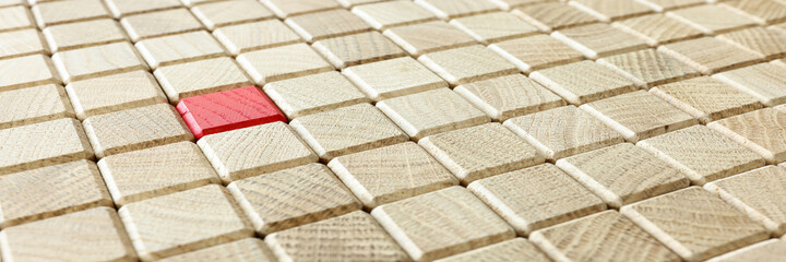 Red wooden cube lying among many other cubes background