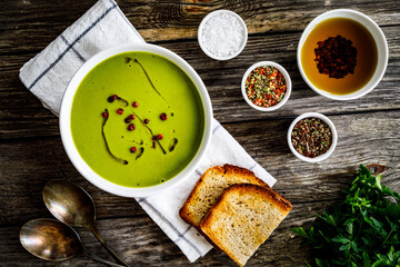 Cream green peas soup on wooden table 