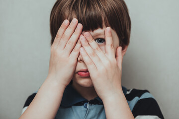 Unhappy kid boy hands hides his face, child mental health concept, world autism awareness day, teen autism spectrum disorder awareness concept - obrazy, fototapety, plakaty