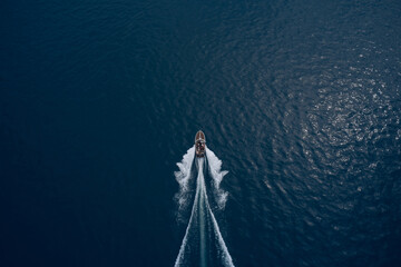 Top view of a boat sailing to the blue sea. Drone view of a boat. Aerial view luxury motor boat. Drone view of a boat the turquoise clear waters.