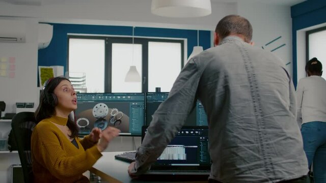 Teamwork sharing ideas about industrial project analysing 3D gears looking at computer with CAD software compering with model from laptop. Industrial engineer and manager working in creative office