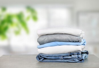 Cotton folded clothes on table indoors. Clean apparel stacked. Stack of clothing.