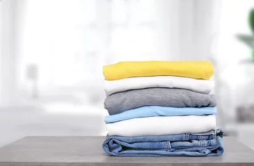 Fotobehang Stack of cotton colorful clothes on table indoors.Stacked apparel.Folded clean clothing. © nys