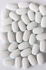 
White pills on a white background. Oval white pills close up. Healthcare and medicine.