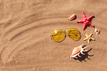 Fototapeta na wymiar Summer or holiday beach vacation background, traveling to the ocean during covid. Sea accessories on sand, starfish, seashells and sun glasses. Flat lay with copy space or place for text
