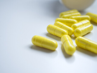 Close up yellow pills with bottle and white background and copy space. Medical concept for sick times