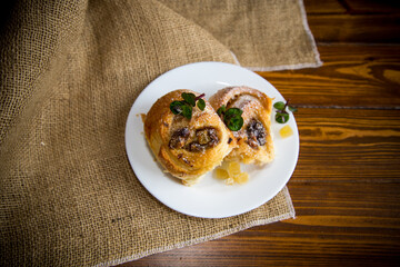 Sweet curled bun with jam, raisins in powdered sugar