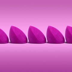 Purple cosmetic blending sponges in a row on a simple backdrop