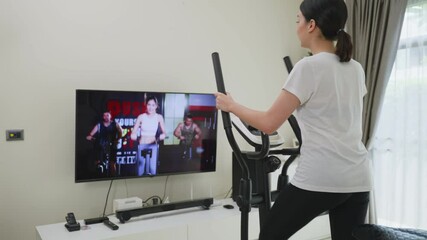 Asian girl doing exercise by learning online from video tutorial.
