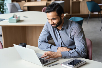Smiling indian executive manager working at home watching online learning training webinar for...