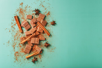 Dark chocolate slices with cinnamon and spices on a pastel green background.