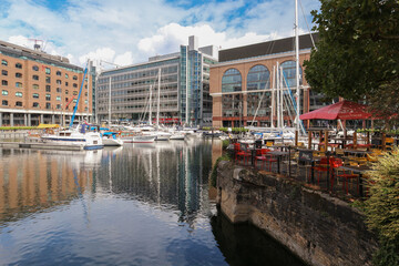 Cafe by the water in St. Katharine Docks Marina, with view on anchored boats and buildings in the...