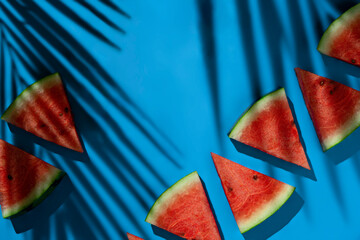 Watermelon slices Top View on a blue background with leaf shadows and copy space