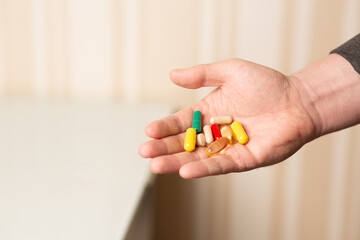 Man holding various pills and daily supplements
