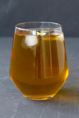 glass of juice.glass cup of iced Herbal chamomile tea on a grey table with copy space. cup of tea with fresh flowers and green leaves on black background.