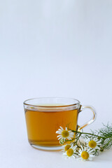 mug of chamomile tea. glass cup of iced Herbal chamomile tea on a white table with copy space. cup of tea with fresh flowers and green leaves on white background. vertical