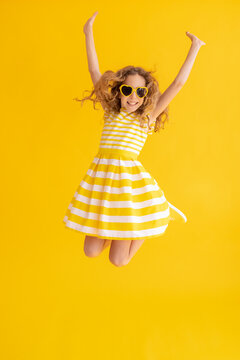 Happy Child Jumping Against Yellow Summer Background