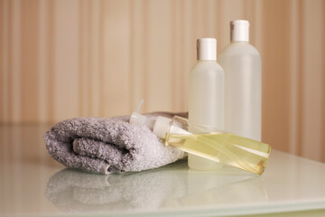 Fototapeta na wymiar Bottles of shampoo, bath foam and micellar oil with towel