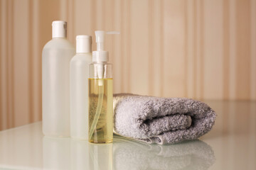 Fototapeta na wymiar Bottles of hair shampoo, shower gel and micellar oil with towel