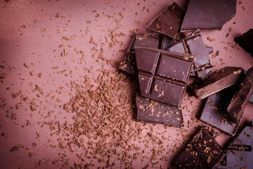 Flat lay of pieces of chocolate bar with chocolate chips on brown background. Broken chocolate...
