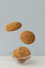 Flying big round cookies and cookies in little roud plate on light grey background. Creative idea of food levitation.
