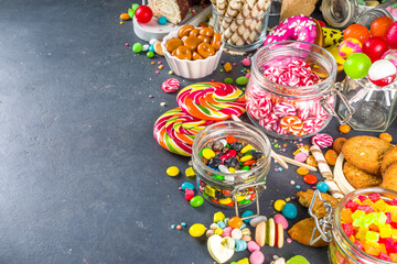 Obraz premium Selection of colorful sweets. Set of various candies, chocolates, donuts, cookies, lollipops, ice cream top view on black concrete background