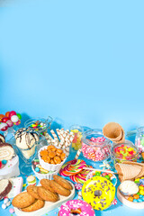Selection of colorful sweets. Set of various candies, chocolates, donuts, cookies, lollipops, ice cream top view on trendy bright blue sunny background