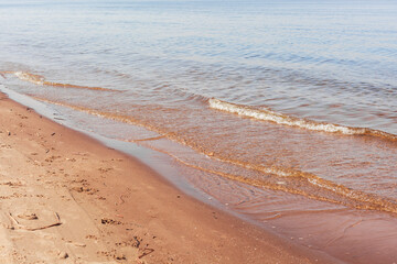 Sandy coast of Volga river in Samara city in spring sunny day. Soft waves on the water surface