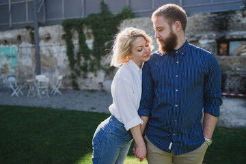 Romantic and happy caucasian couple in casual clothes walking together through the city streets. Love, relationships, romance, happiness concept. Man and woman holding hands and smiling.