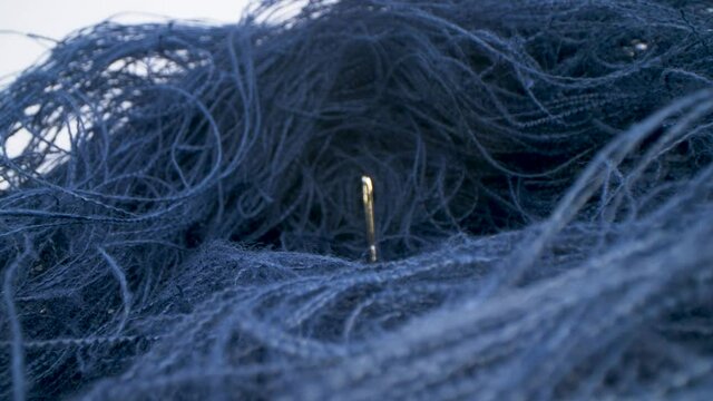 Macro view of needle surrounded by threads. Needle in a haystack. Moving shot.
