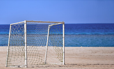 Goal soccer near sea. Goalpost on sand beach on background of blue sea and sky in summer.