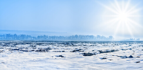 arable field covered with snow with trees on the horizon