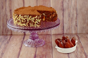 Vegan raw chocolate cake with dates, almond nuts, mashed banana and cacao powder on cake stand