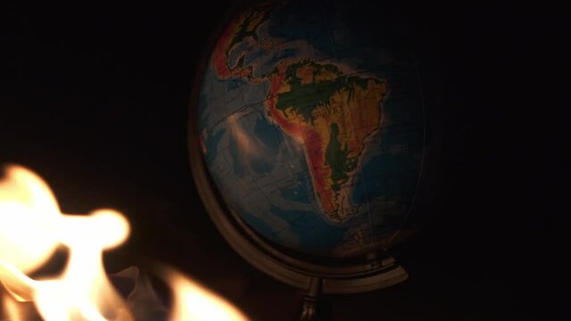 Close up of burning globe on destructed floor with a lot of rocks. Bright fire with a lot of smoke above view