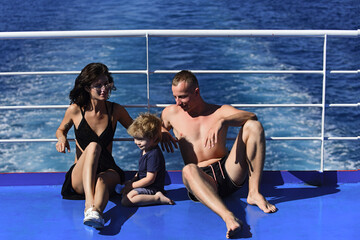 Family with child on summer vacation. Father, mother and son on cruise liner with sea waves on background. Family rest concept. Family travelling on cruise ship on sunny day.